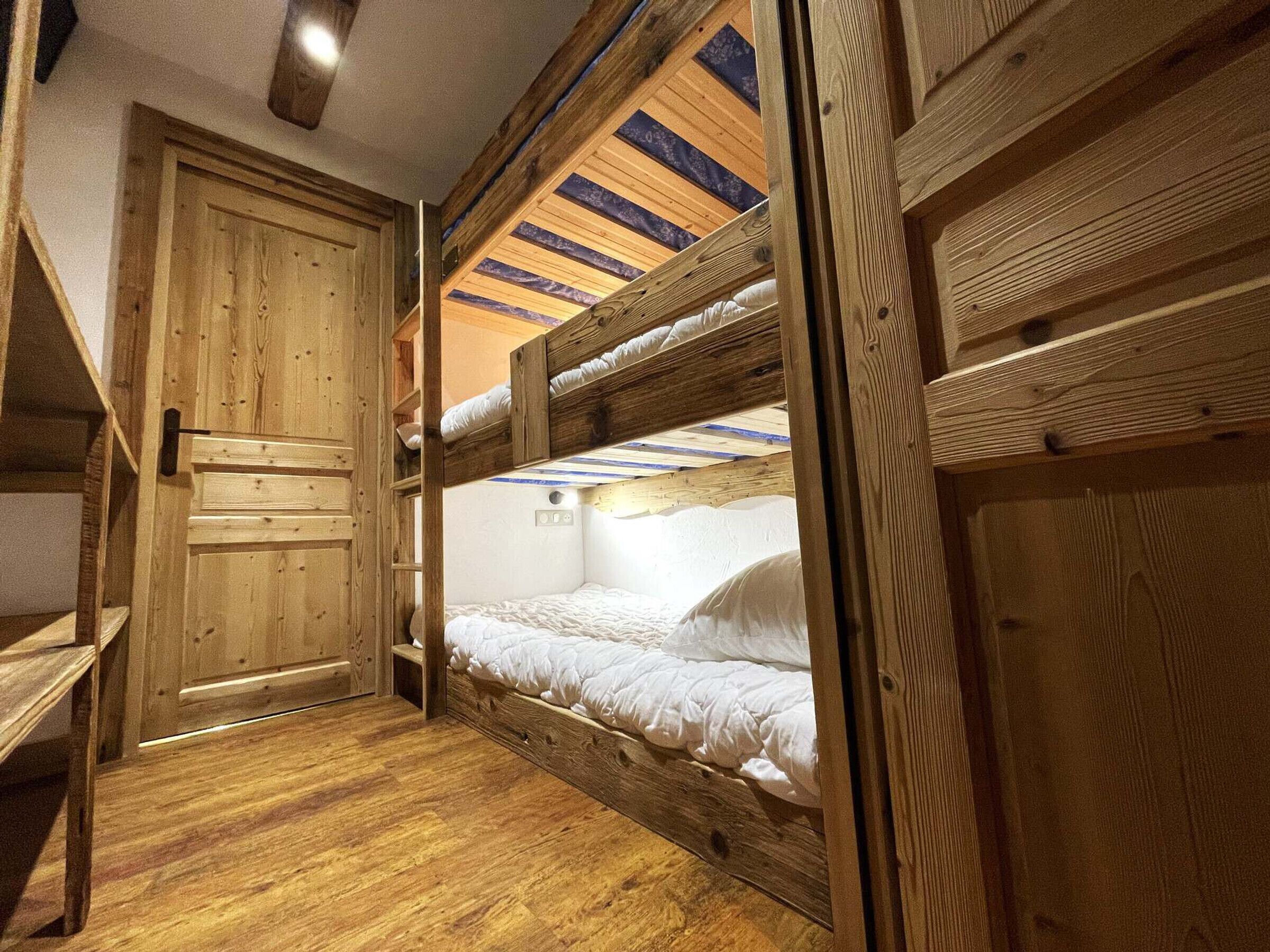 A wooden bunk bed room with a door and a shelf.