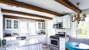 Une cuisine spacieuse avec des meubles blancs, un grand îlot central, une cuisinière à gaz et un four à micro-ondes.