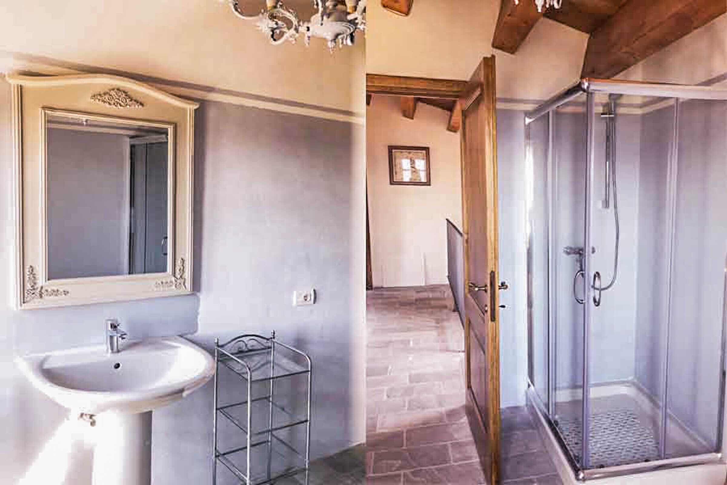 A bathroom with a sink, mirror, shower, and tiled floor.
