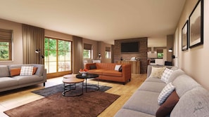 A spacious living room with a grey sofa, a brown sofa, and a coffee table. There is a kitchen area with a TV mounted on the wall.