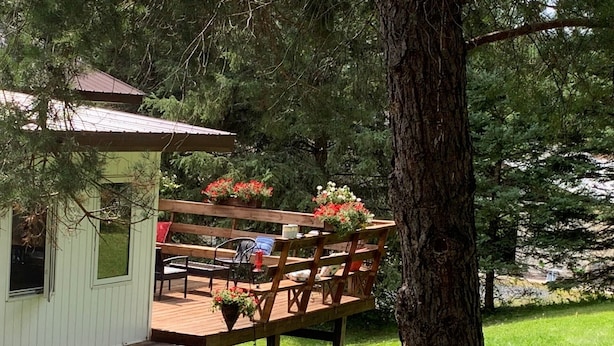 A wooden deck with a small building, outdoor seating, and potted plants. - Rustic Canadian Fishing Experience (Dryden)