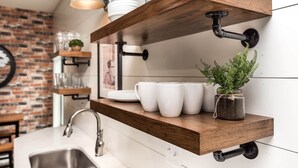 Une cuisine avec des murs en briques apparentes, des étagères en bois et un luminaire suspendu.