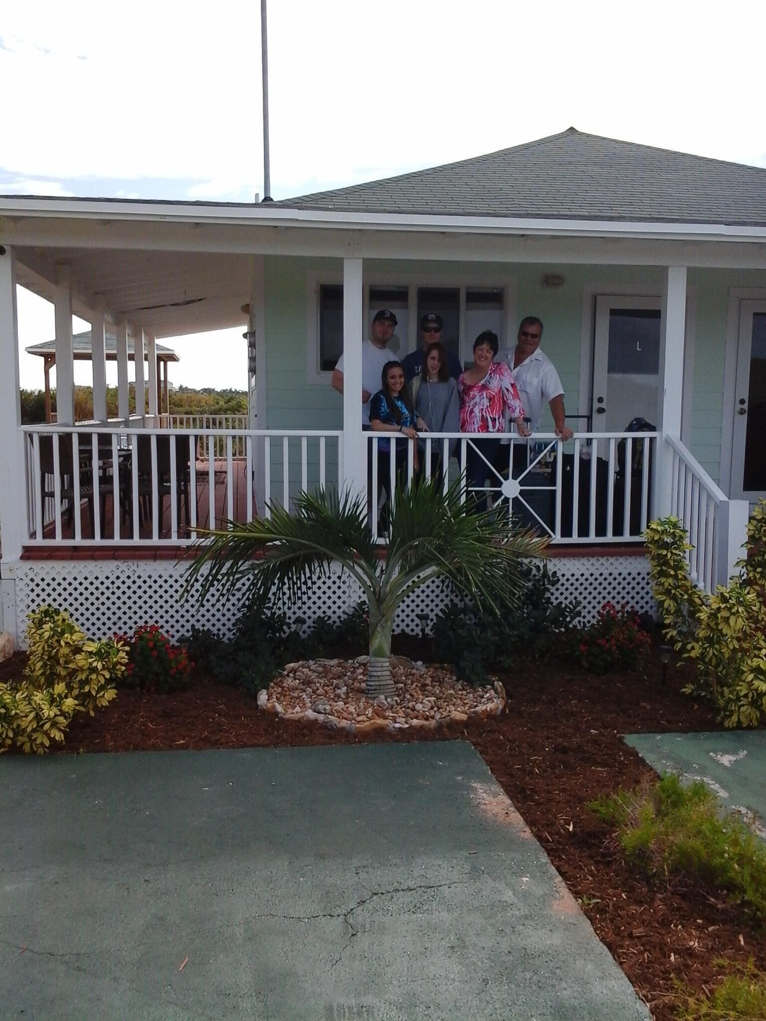 A house with a porch, a small garden, and a covered area with a gazebo.