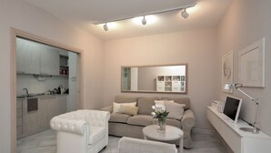A modern living room with a sofa, a dining table, and a kitchen area with cabinets and a sink.