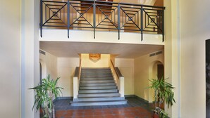 A staircase with a geometric railing, potted plants, and a tiled floor.
