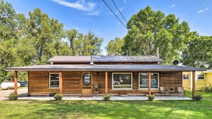 A wooden cabin with a porch, a large window, and a satellite dish. - Family Home w/ Hot Tub - Walk to Johnson Lake! (Johnson Lake)