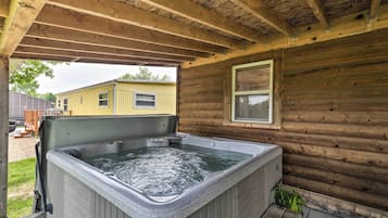 Uma cabana de madeira com hidromassagem sob um alpendre coberto.