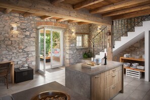 A rustic kitchen with stone walls, wooden beams, and a stone staircase. - Villa Flavia - Renovated stone villa with private pool (Čepljani)