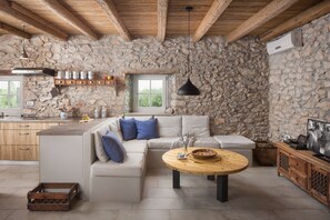 A rustic kitchen with stone walls, wooden beams, a stone countertop, and a wooden dining table. - Villa Flavia - Renovated stone villa with private pool (Čepljani)