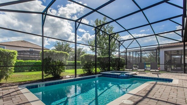 An indoor swimming pool with a clear blue water, surrounded by a glass enclosure, and a patio area with chairs. - EV_1447 - 6 Bed 6 Bath Villa with Screened Private Pool, Games Room, Kids Rooms (Davenport)