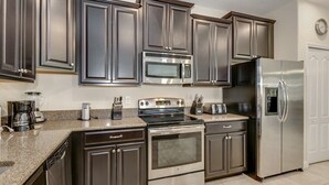 A modern kitchen with stainless steel appliances, dark cabinetry, and granite countertops. - EV_1447 - 6 Bed 6 Bath Villa with Screened Private Pool, Games Room, Kids Rooms (Davenport)