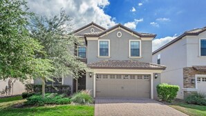 A two-story house with a garage, a brick driveway, and a well-maintained lawn. - EV_1447 - 6 Bed 6 Bath Villa with Screened Private Pool, Games Room, Kids Rooms (Davenport)