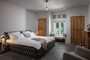 Un dormitorio con una cama grande, un armario de madera y una ventana con vistas a zonas verdes.