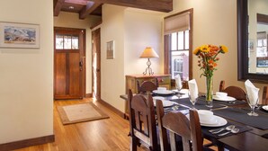 A dining area with a wooden table set for four, a vase of flowers, and a lamp on a side table. - Short stroll to the historic plaza, Canyon Road & Railyard District Restaurants (Santa Fe)