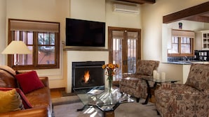 A living room with a fireplace, leather sofa, patterned armchairs, a glass coffee table, and a television. - Short stroll to the historic plaza, Canyon Road & Railyard District Restaurants (Santa Fe)