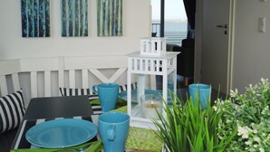 A dining area with a white bench, blue tableware, and a white lantern. - ⭐unique location at the beginning of the pier with unobstructed all-round water view⭐ (Kappeln/Ostseeresort Olpenitz)