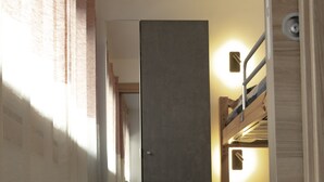 A narrow hallway with wooden flooring, a central door, and a bunk bed on the right. - Bright and Cozy Two-room apartment with balcony overlooking the Matterhorn (Breuil-Cervinia)