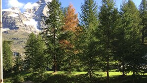 A parking area with concrete barriers, a view of a mountain range, and evergreen trees. - Bright and Cozy Two-room apartment with balcony overlooking the Matterhorn (Breuil-Cervinia)