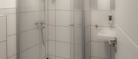 Een moderne badkamer met een douchecabine van glas, een wit wastafelmeubel en een toilet.