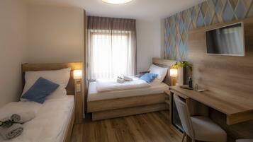 A hotel room with a bed, a desk, and a TV.
