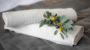 Une serviette blanche, soigneusement pliée et ornée d’un motif texturé, est posée sur une surface rembourrée de couleur grise.