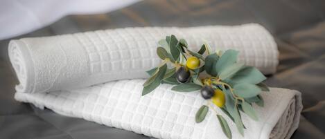 A neatly folded white towel with a textured pattern, placed on a grey upholstered surface.