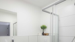 Une salle de bain moderne avec une douche à parois de verre, un lavabo blanc et des toilettes.