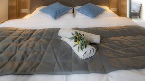 Un lit bien fait, avec une couette grise, du linge de lit blanc et deux oreillers bleus.