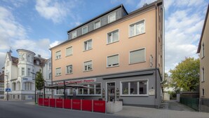 Un immeuble à plusieurs étages qui abrite au rez-de-chaussée un restaurant appelé « Balkan Grill - Pizzeria ».