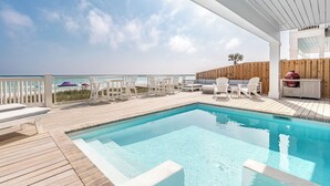 Ein Poolbereich mit Holzterrasse, Liegestühlen und Blick auf den Ozean.