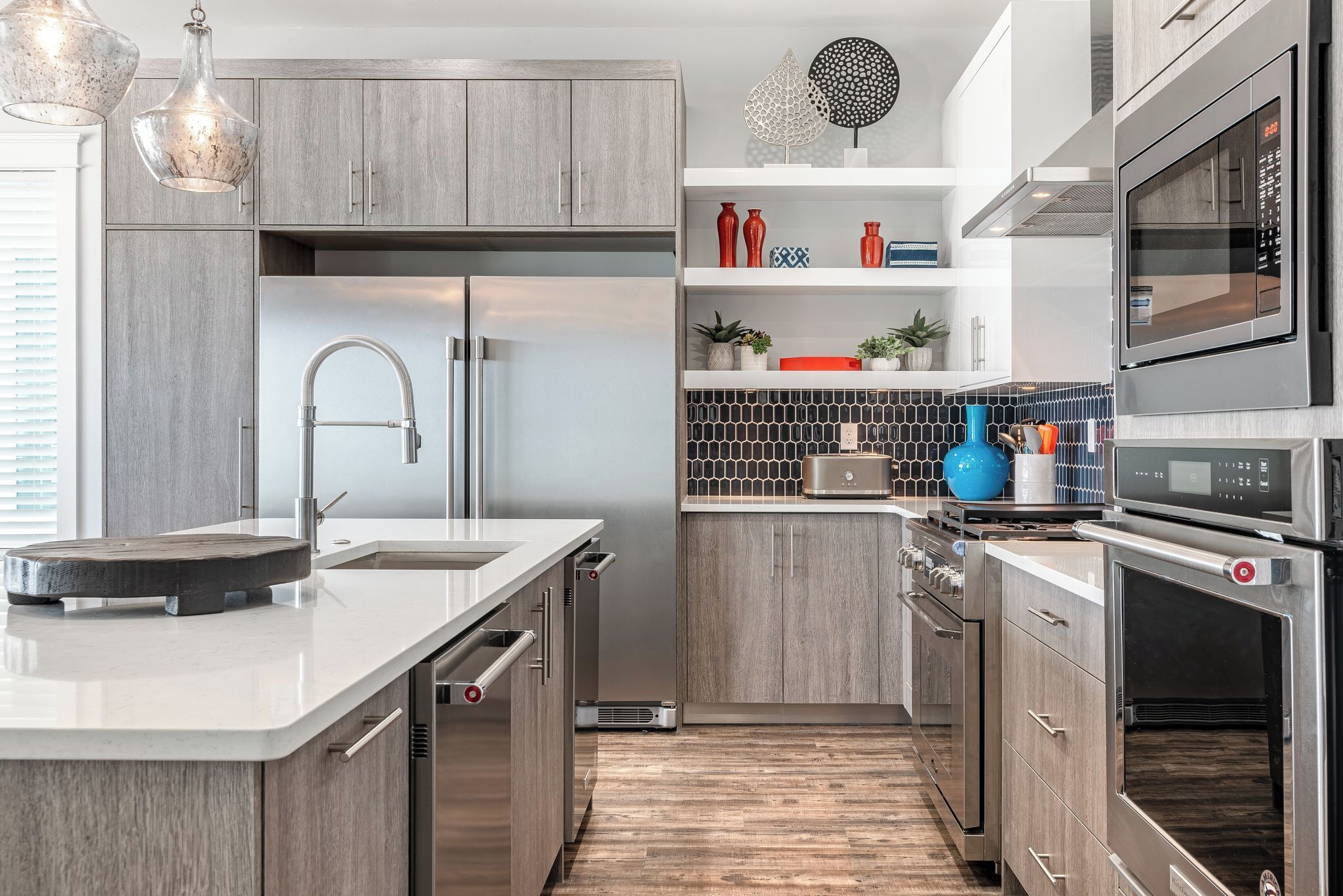 A modern kitchen with grey cabinets, stainless steel appliances, and a central island.