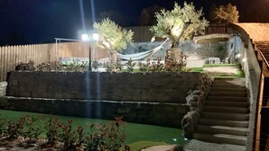 Una escalera de piedra conduce a una terraza de madera con una hamaca y un sillón hamaca.