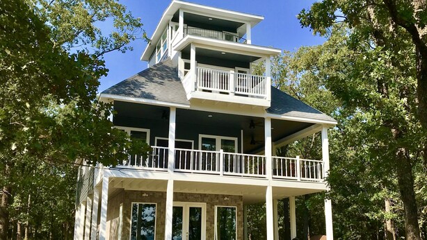 A two-story house with a balcony, large windows, and a stone foundation. - Tree Top Lake Views with lake access for swimming fishing boating 250 ft away! (Pottsboro)