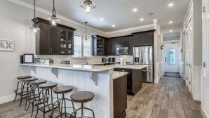 A modern kitchen with dark cabinets, stainless steel appliances, and a bar area with stools.
