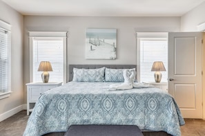 A bedroom with a bed, two bedside tables, a nightstand, a bench, and a door. - 🌊 Salty Shores | Resort-Style Pool w/ Waterfalls | Beach Access | Walk to Beach (Miramar Beach)