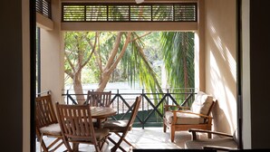 Un balcon avec des meubles en bois, une vue sur les arbres et un bâtiment en arrière-plan.