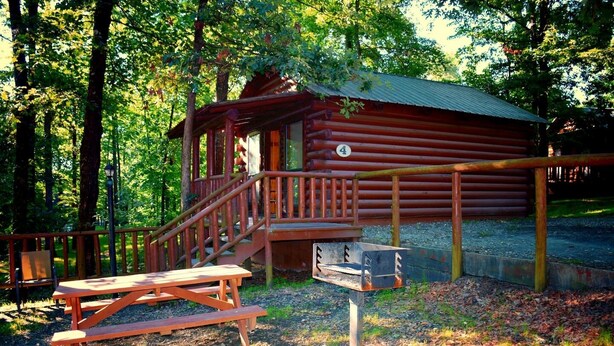 A rustic cabin with a wooden deck and a picnic table. - Cozy Cabin with Fire Pit pavilion near boat ramp (Broken Bow)