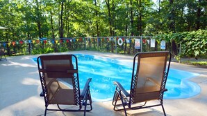 Two metal-framed chairs with mesh backs facing a swimming pool. - Cozy Cabin with Fire Pit pavilion near boat ramp (Broken Bow)