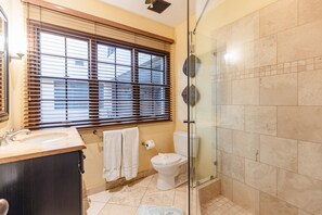A bathroom with a glass shower enclosure, a toilet, and a sink with a vanity.