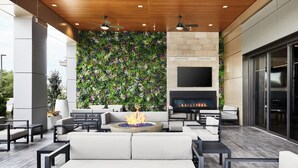 An outdoor patio area with a fire pit, seating, and a TV mounted on the wall. - AC Hotel Bridgewater (Bridgewater)