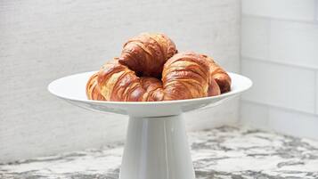 A white ceramic plate holding three croissants on a marble countertop.