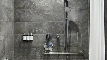 A modern shower with a handheld showerhead, a wall-mounted faucet, and a glass-enclosed shower area.