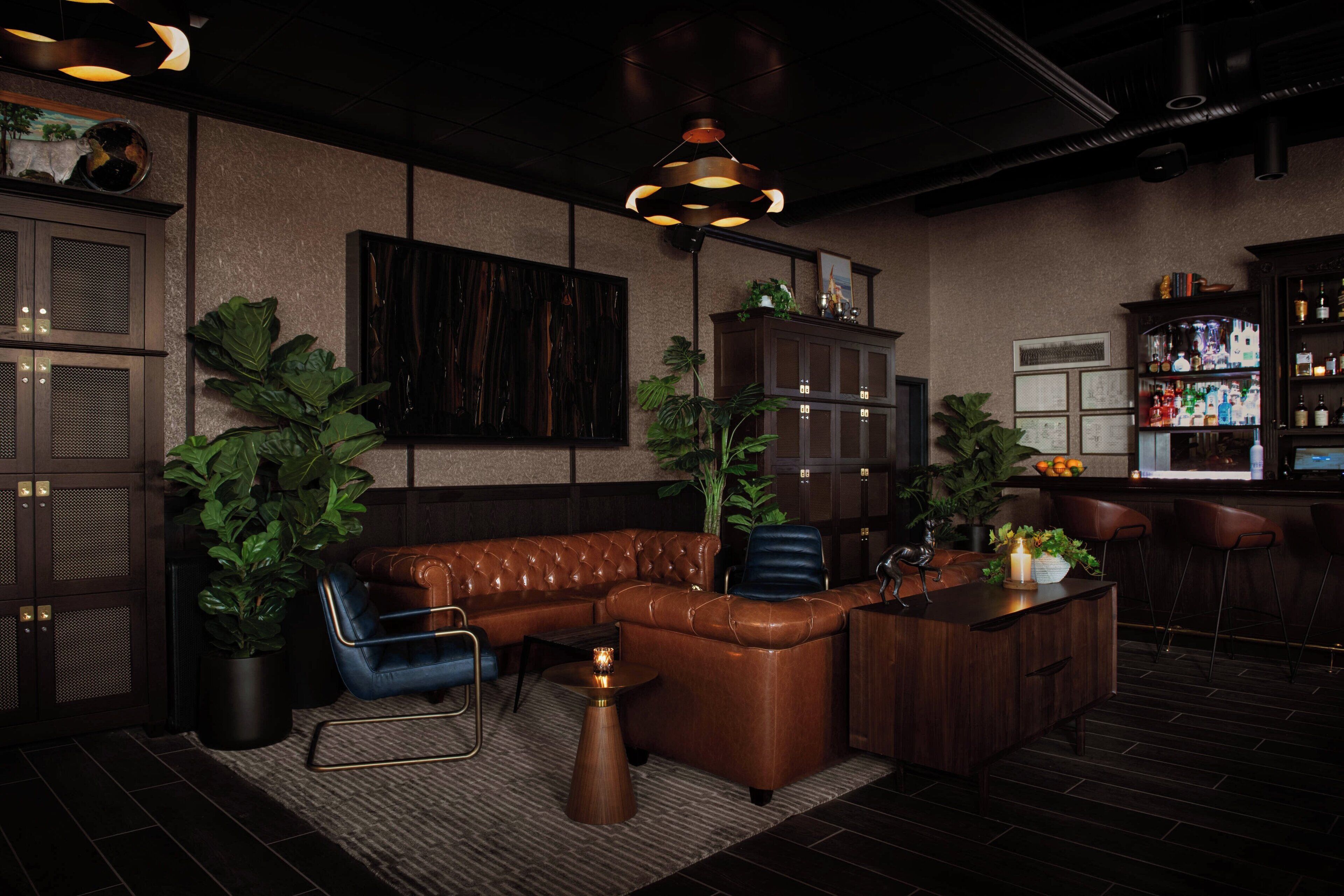 A modern bar area with leather seating, a bar counter, and ambient lighting.