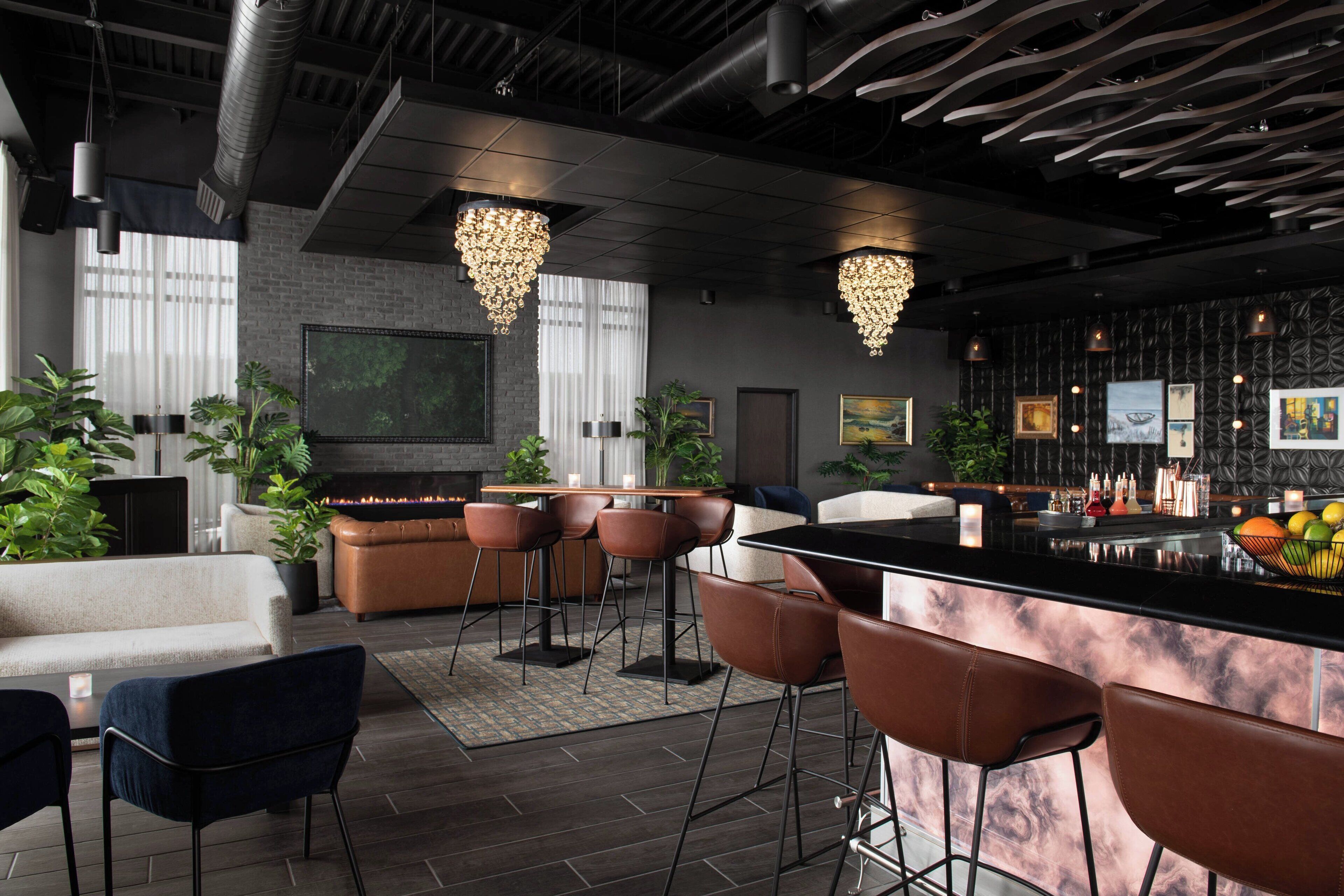 A modern bar area with leather bar stools, a black countertop, and pendant lighting.