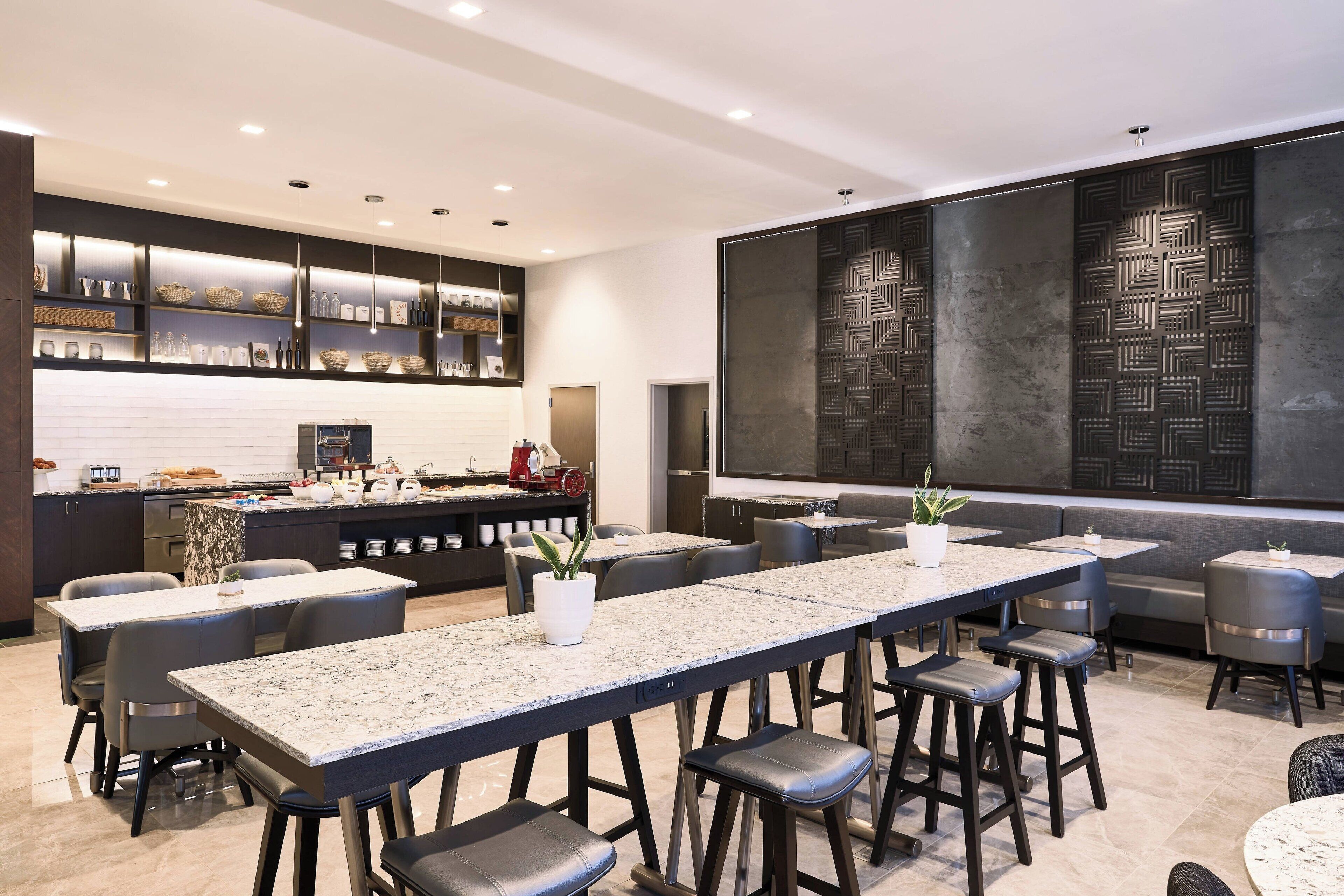 Un restaurante moderno con una barra alargada, varias áreas de estar y paneles decorativos en las paredes.