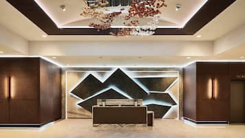 A modern reception area with a reception desk, a geometric wall design, and a chandelier.