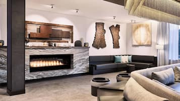 A modern living room with a fireplace, a black sofa, and a large abstract painting on the wall.