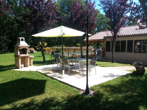 A patio with a grill, outdoor table, and umbrella.