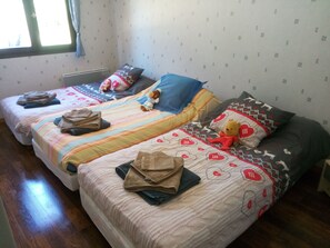 A room with two beds, each with a different patterned bedspread and pillows. There are folded towels on each bed.
