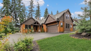 A two-story house with a garage, surrounded by tall trees and a well-maintained lawn.